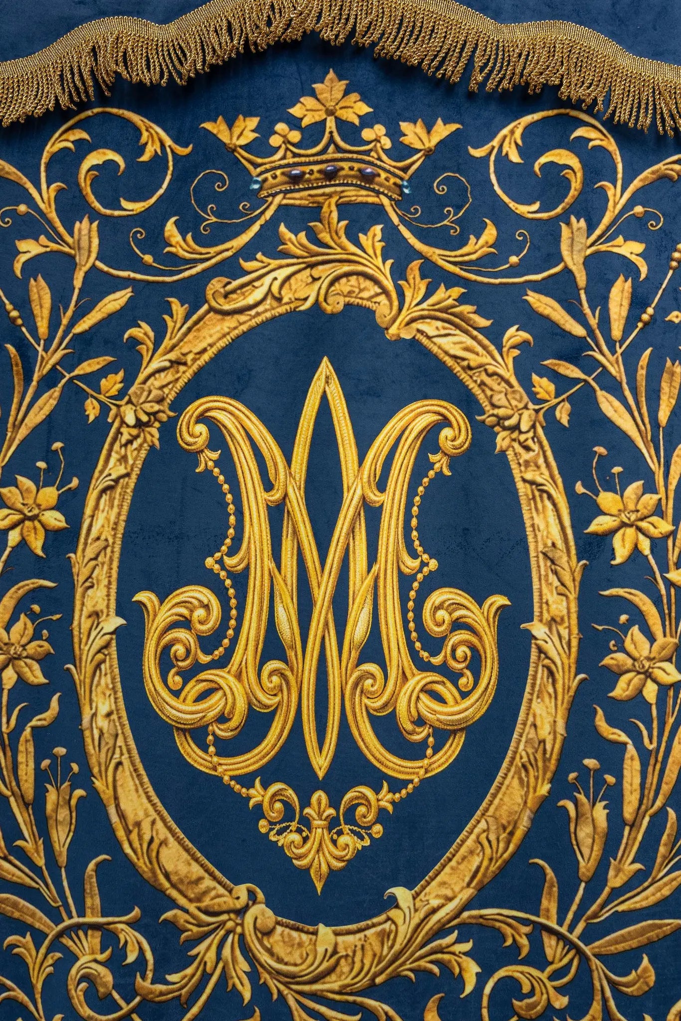 Double-sided blue processional banner with an image of Our Lady of the Immaculate Conception on one side and a Marian monogram on the other, both surrounded by gold floral ornamentation and finished with gold fringes.