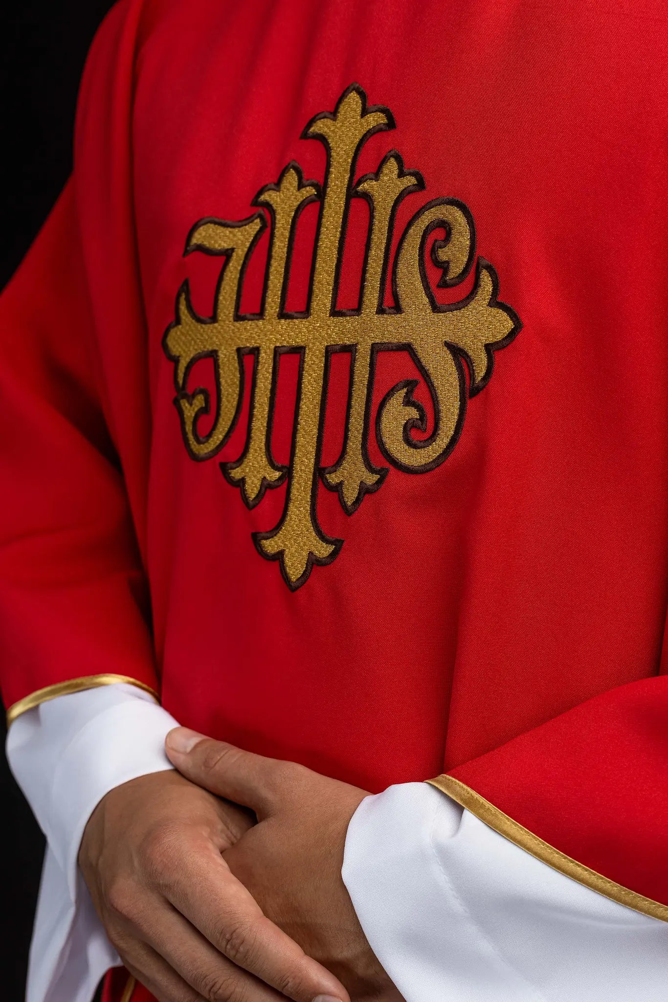 Red chasuble with gold IHS embroidery on the front and back, finished with gold trim and a V-neckline.