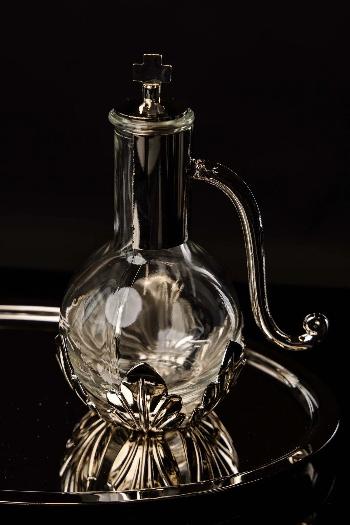 Silver liturgical cruet with cross finial and curved handle, front view