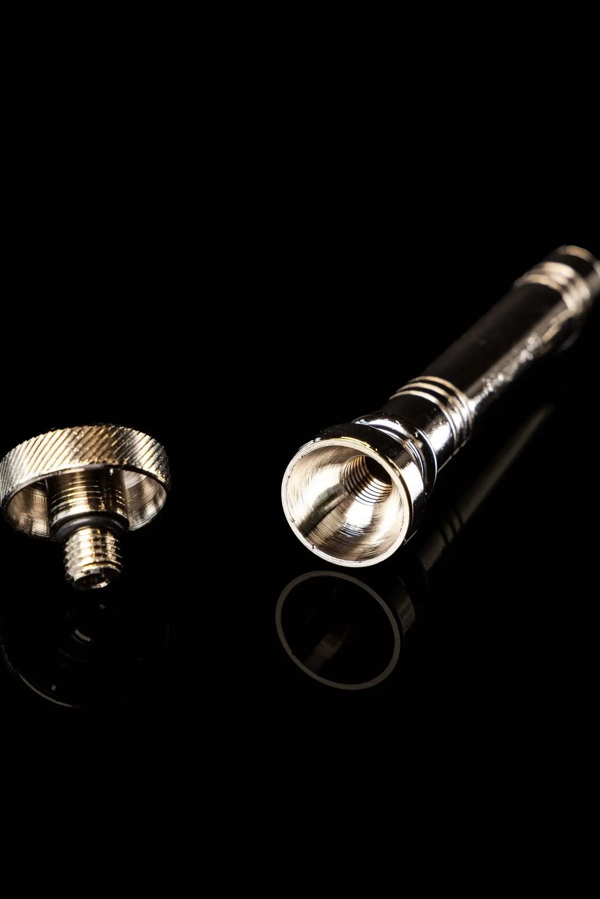 Silver aspergillum with threaded interior and ridged end cap, close-up view