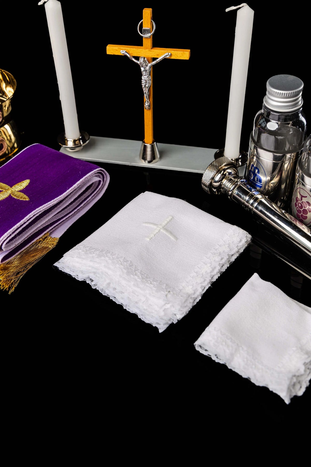 Valigetta liturgica bordeaux con candele, croce, bottiglie e tessili, dettaglio del corredo
