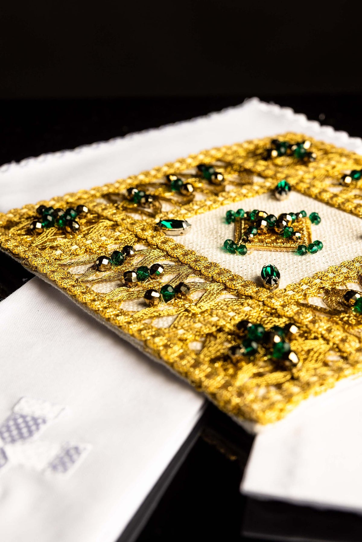 Branco conjunto de alfaias litúrgicas com pedras naturais, bordado dourado e cruz, vista aproximada