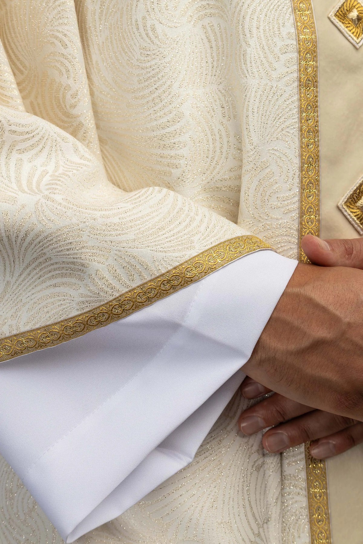 Bianco casula con croce ricamata e pietre naturali, dettaglio del bordo della manica