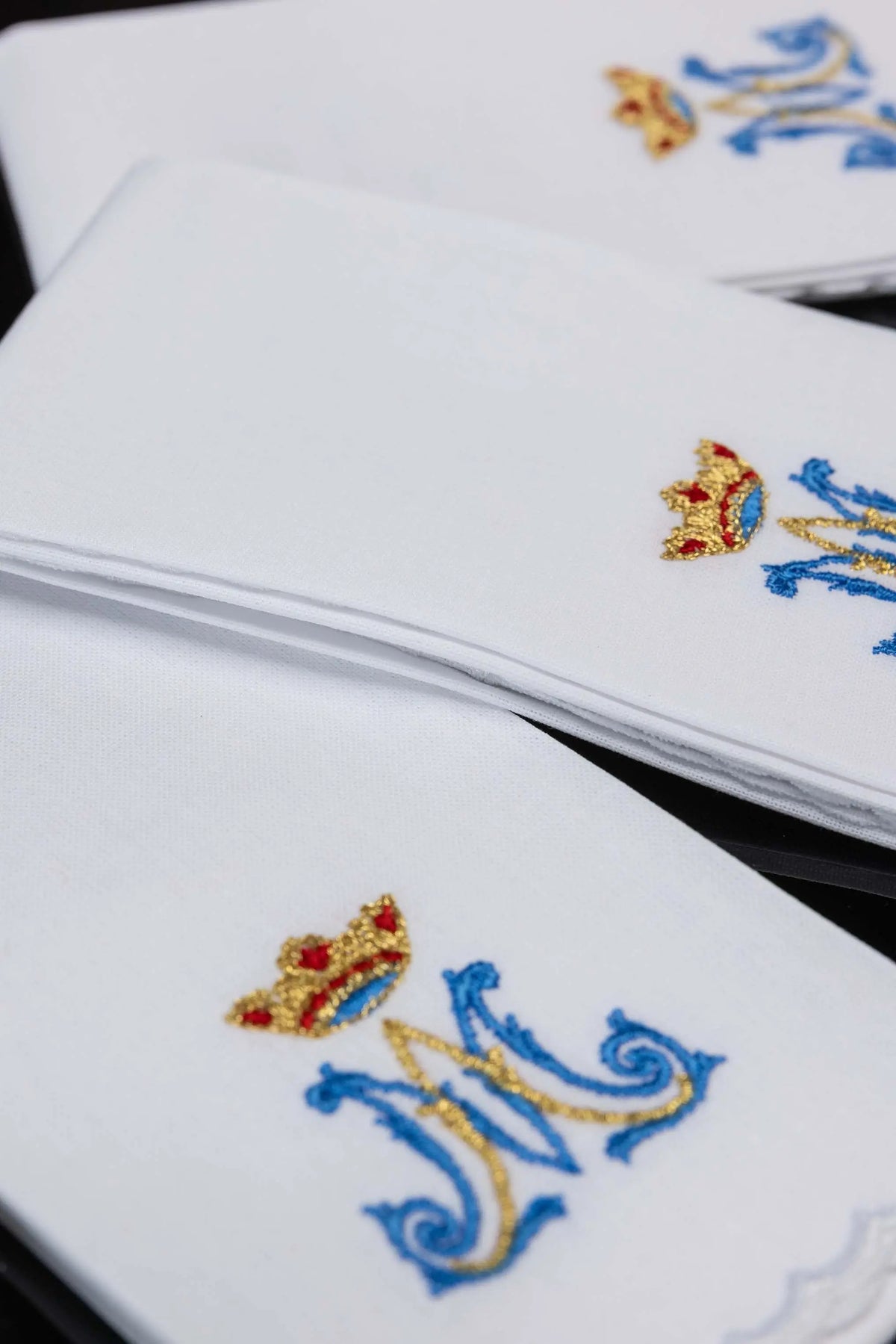 White purificators with Marian “M” monogram and crown embroidery, stacked close-up