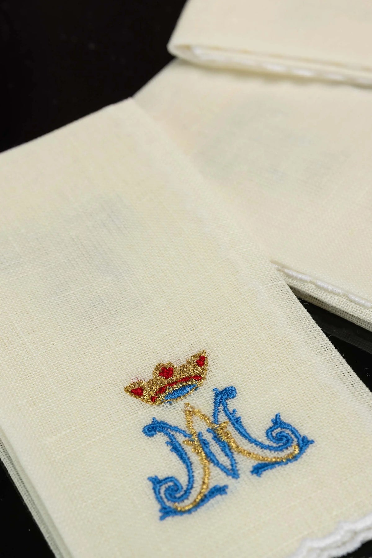 Ecru linen purificator with crowned Marian monogram, close-up view