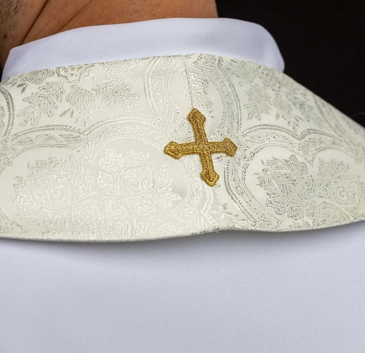 Ecru priest stole with a gold cross, neck detail close-up
