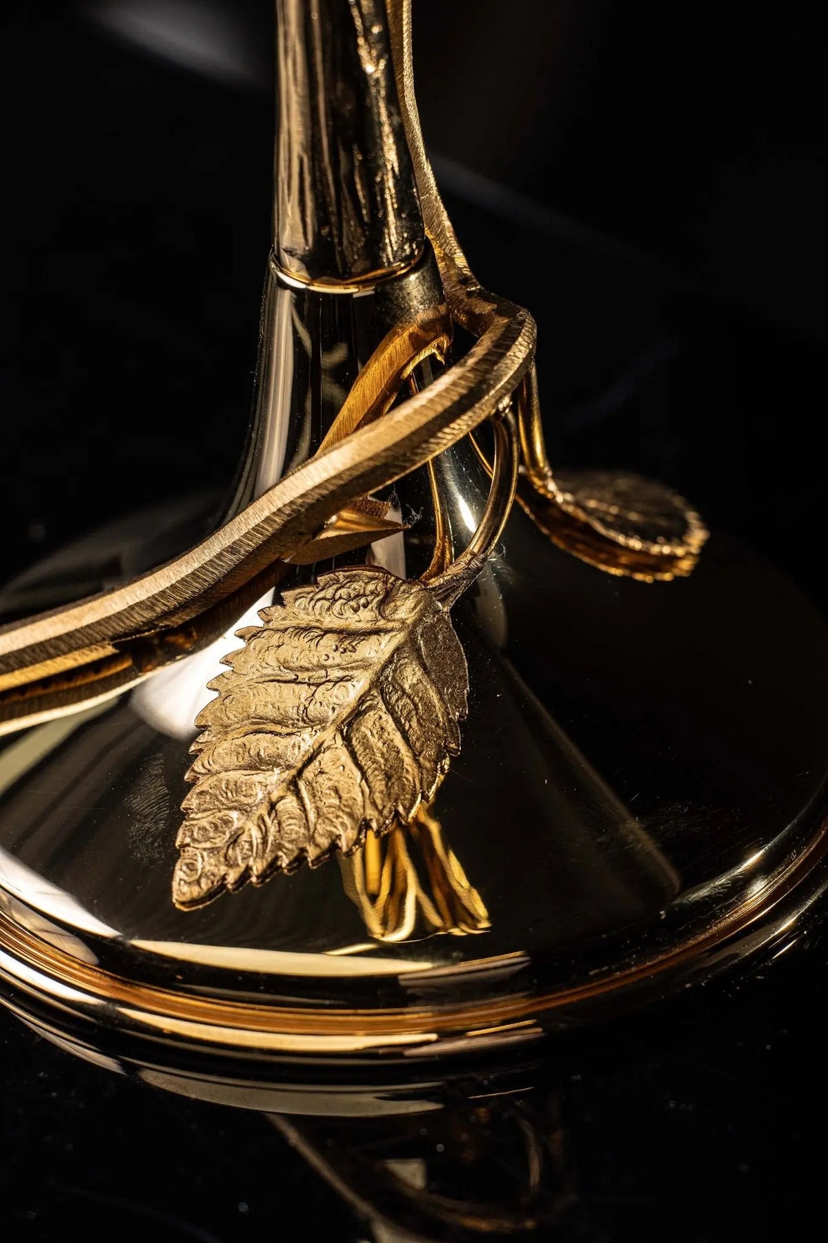 Relicário dourado com cruz e coroa de espinhos, detalhe da base e ornamento lateral