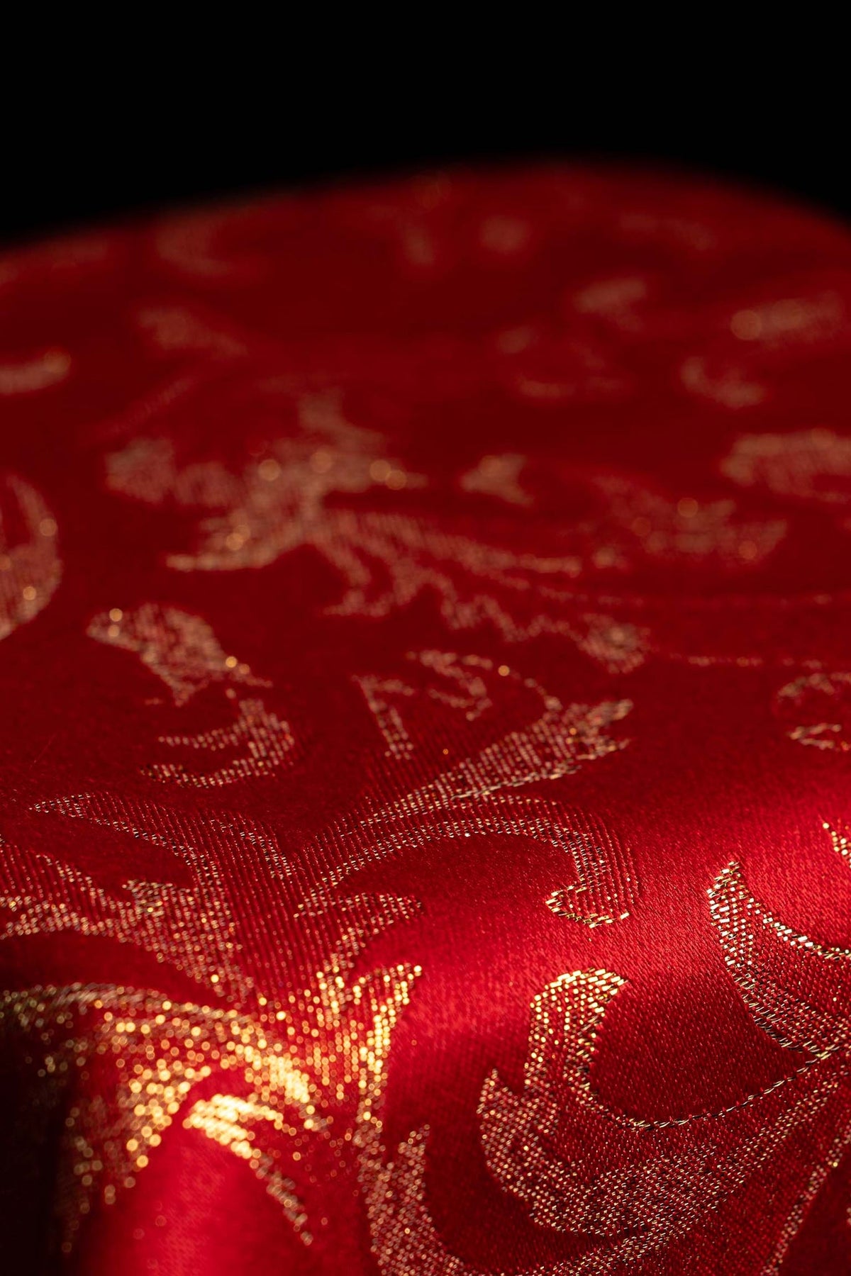 Red chalice veil with gold jacquard scrollwork and embroidered cross, close-up