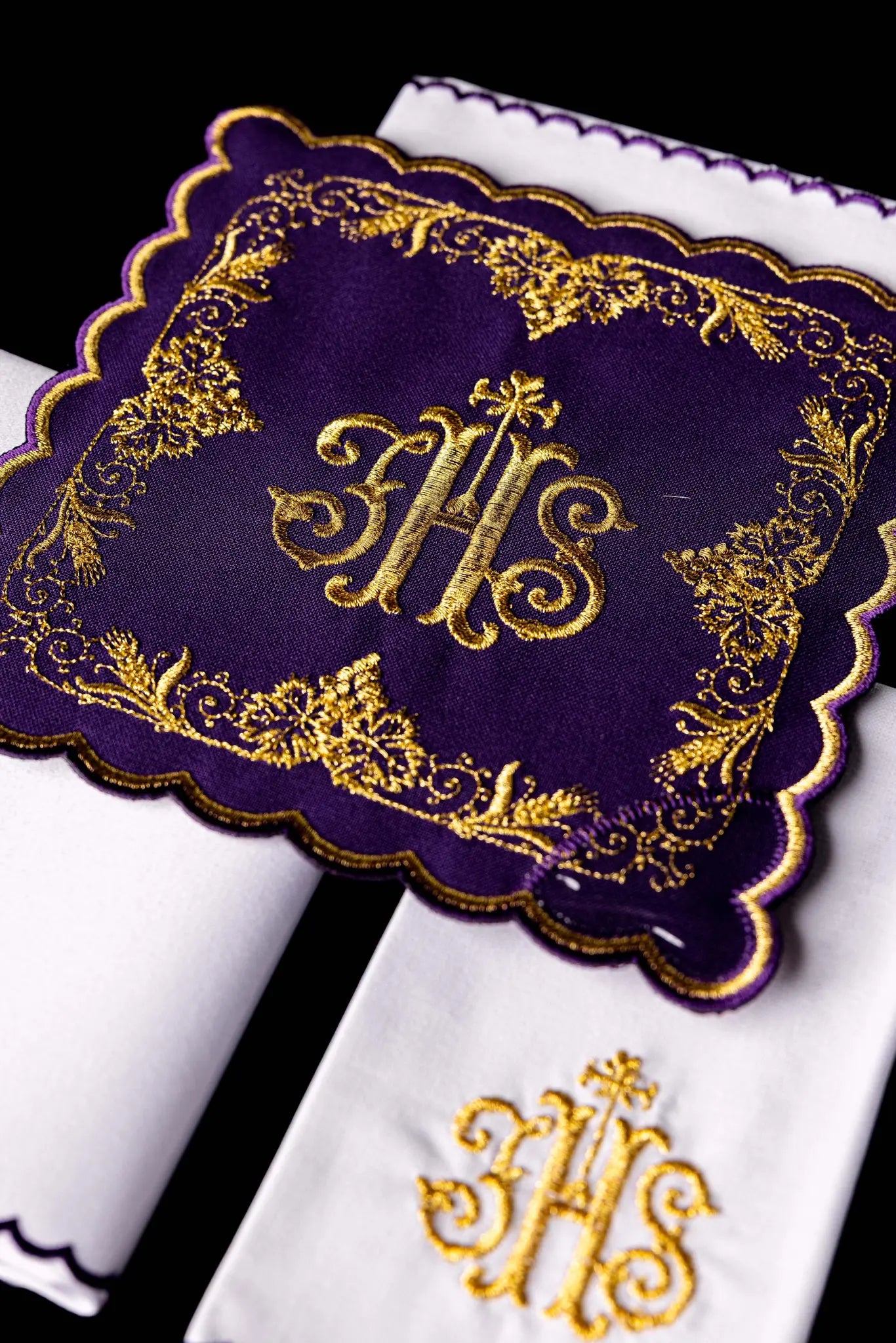 Purple chalice linen set with gold IHS embroidery, vine leaves, and wheat sheaves. Includes a purple pall, white corporal with IHS, and white purificator and lavabo towel with gold crosses and purple scalloped edges.