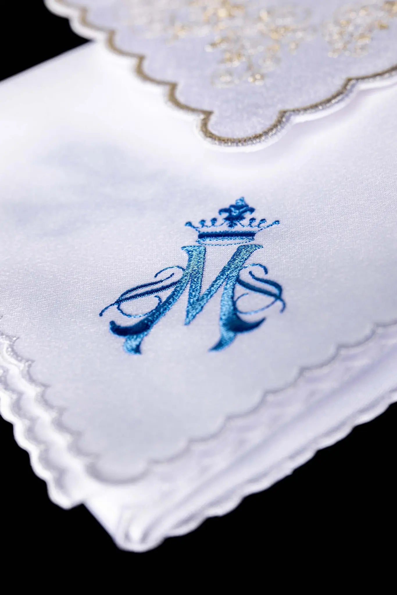 White chalice linen set with Marian monogram embroidery in blue and gold, including pall, corporal, purificator, and lavabo towel.