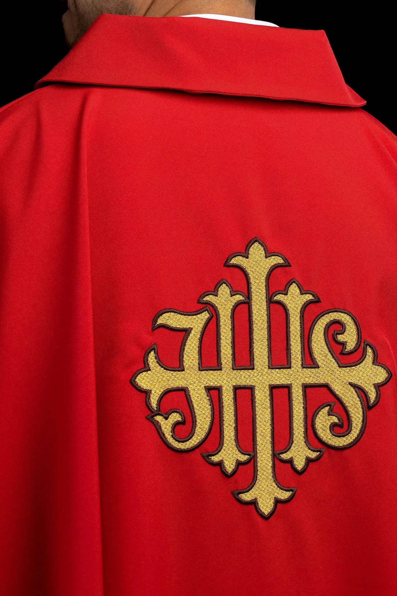 Red chasuble with gold IHS embroidery on the front and back, finished with gold trim and a V-neckline.