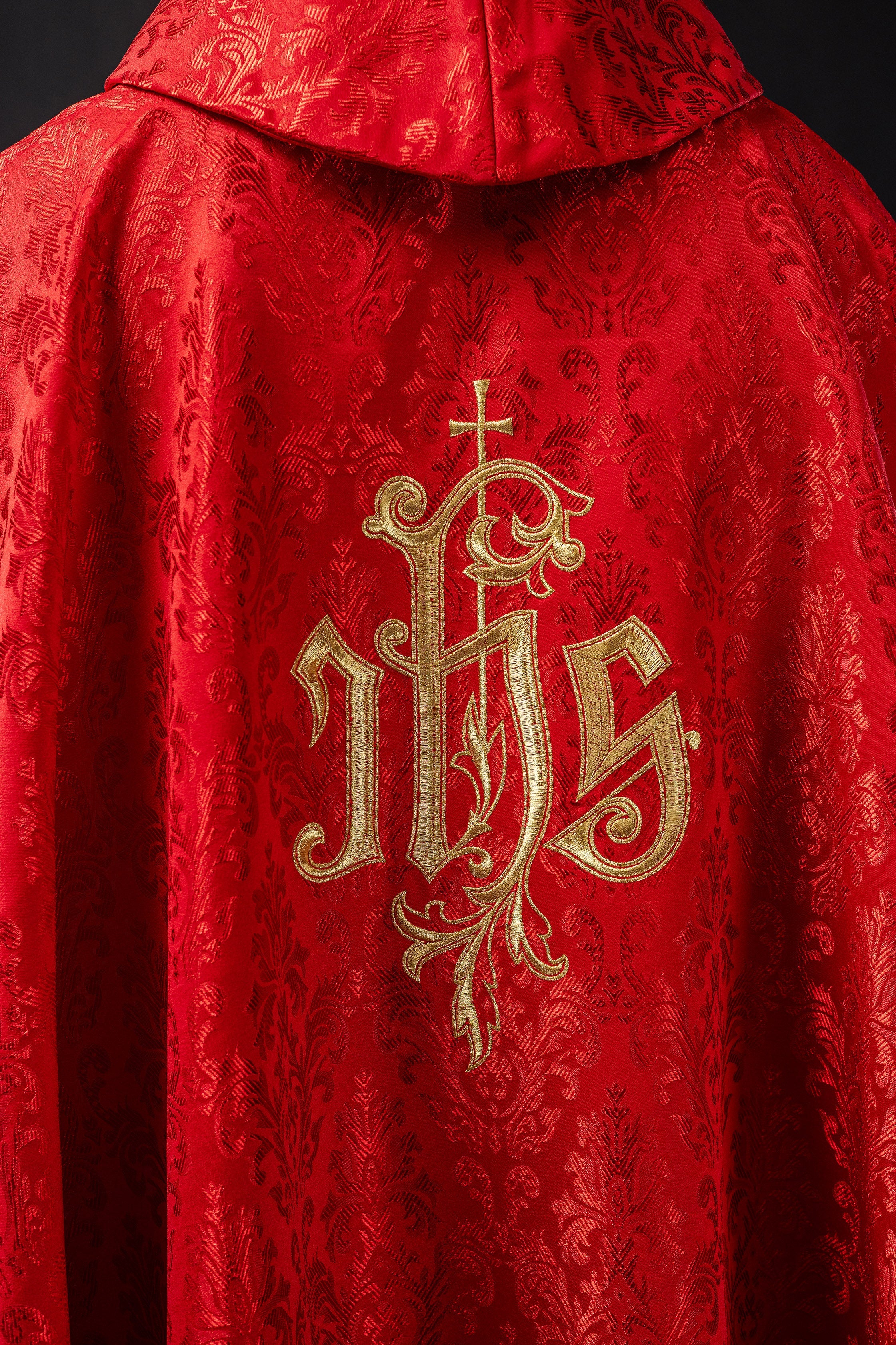 Red chasuble with embroidered IHS motif on decorative fabric