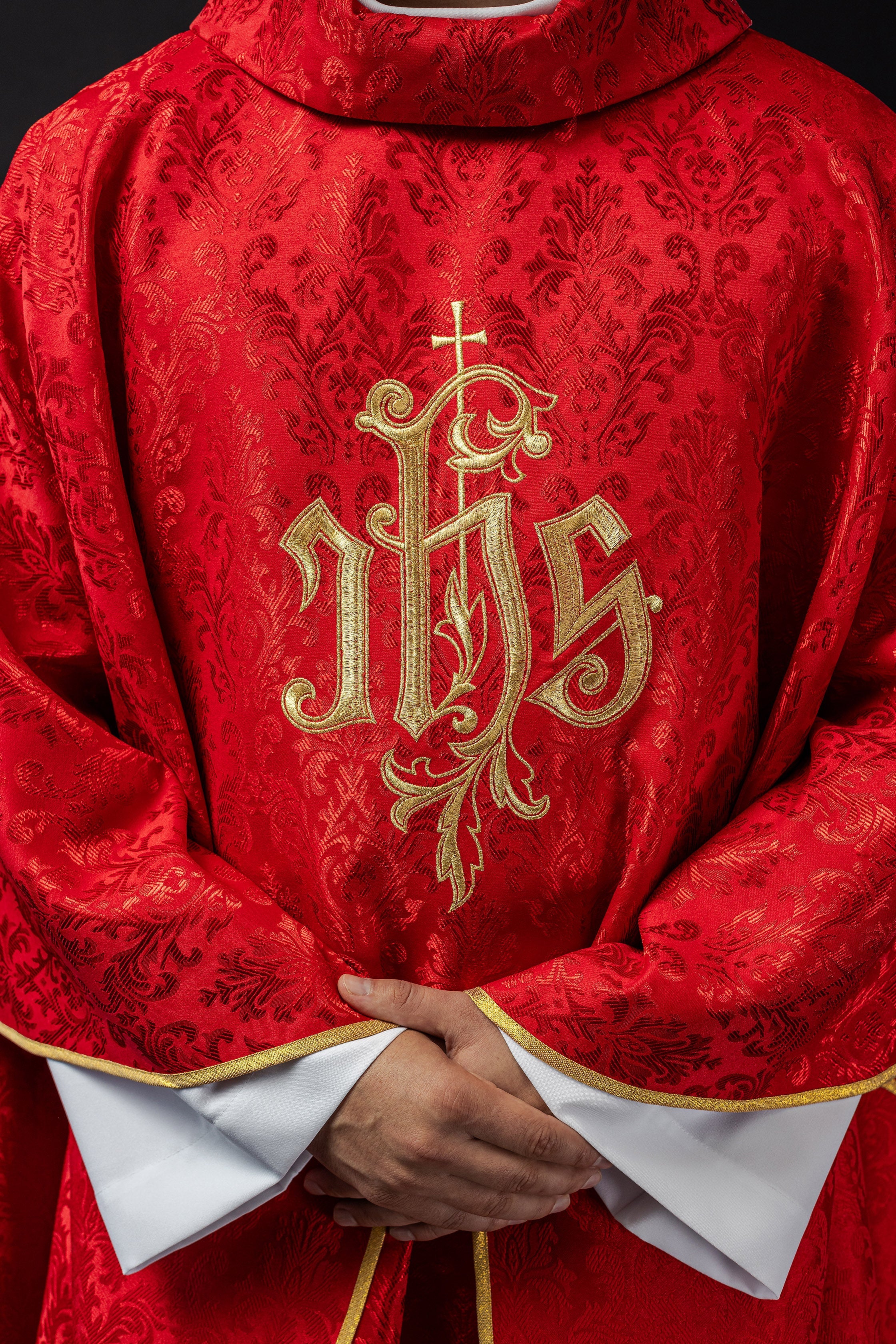 Red chasuble with embroidered IHS motif on decorative fabric