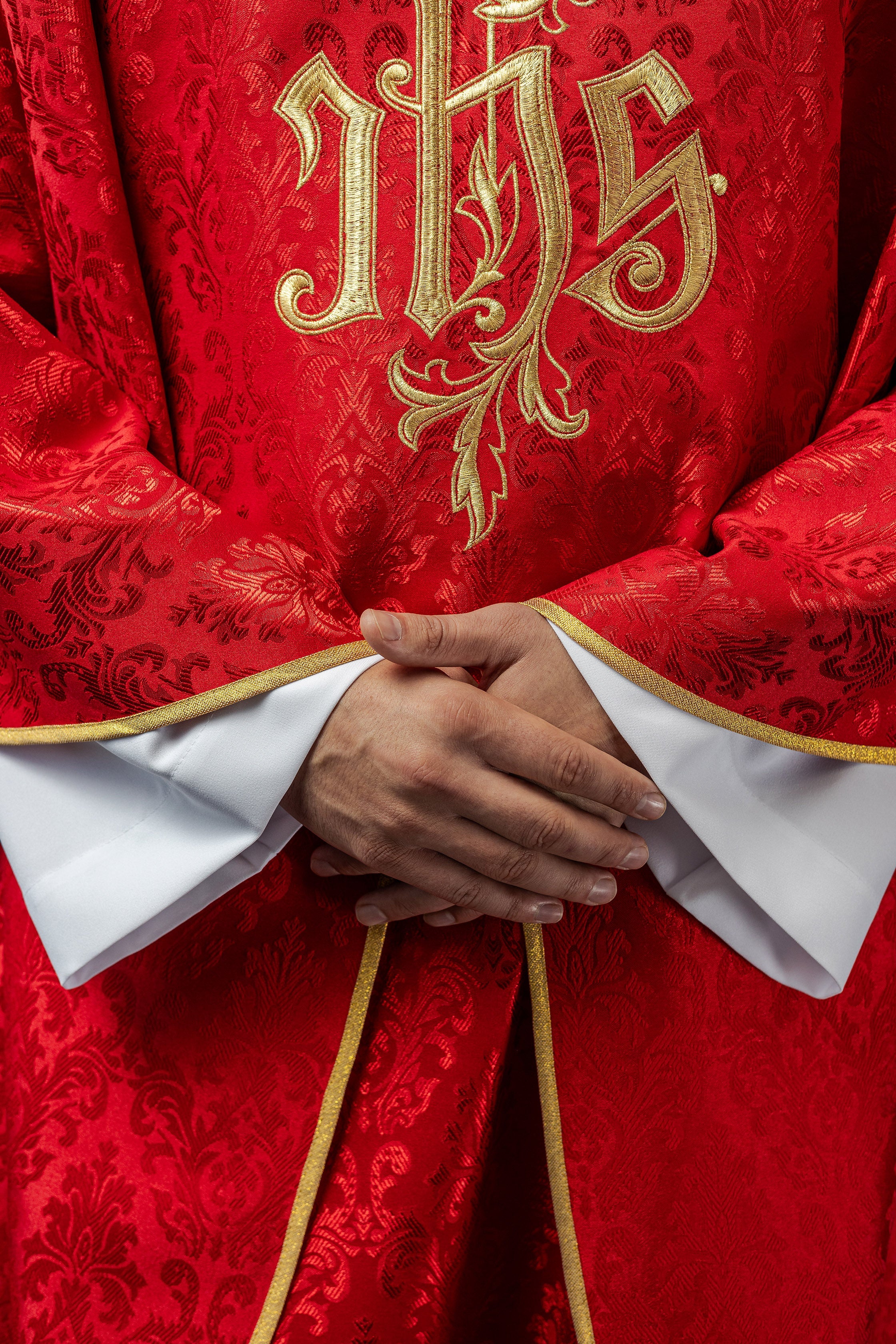 Red chasuble with embroidered IHS motif on decorative fabric