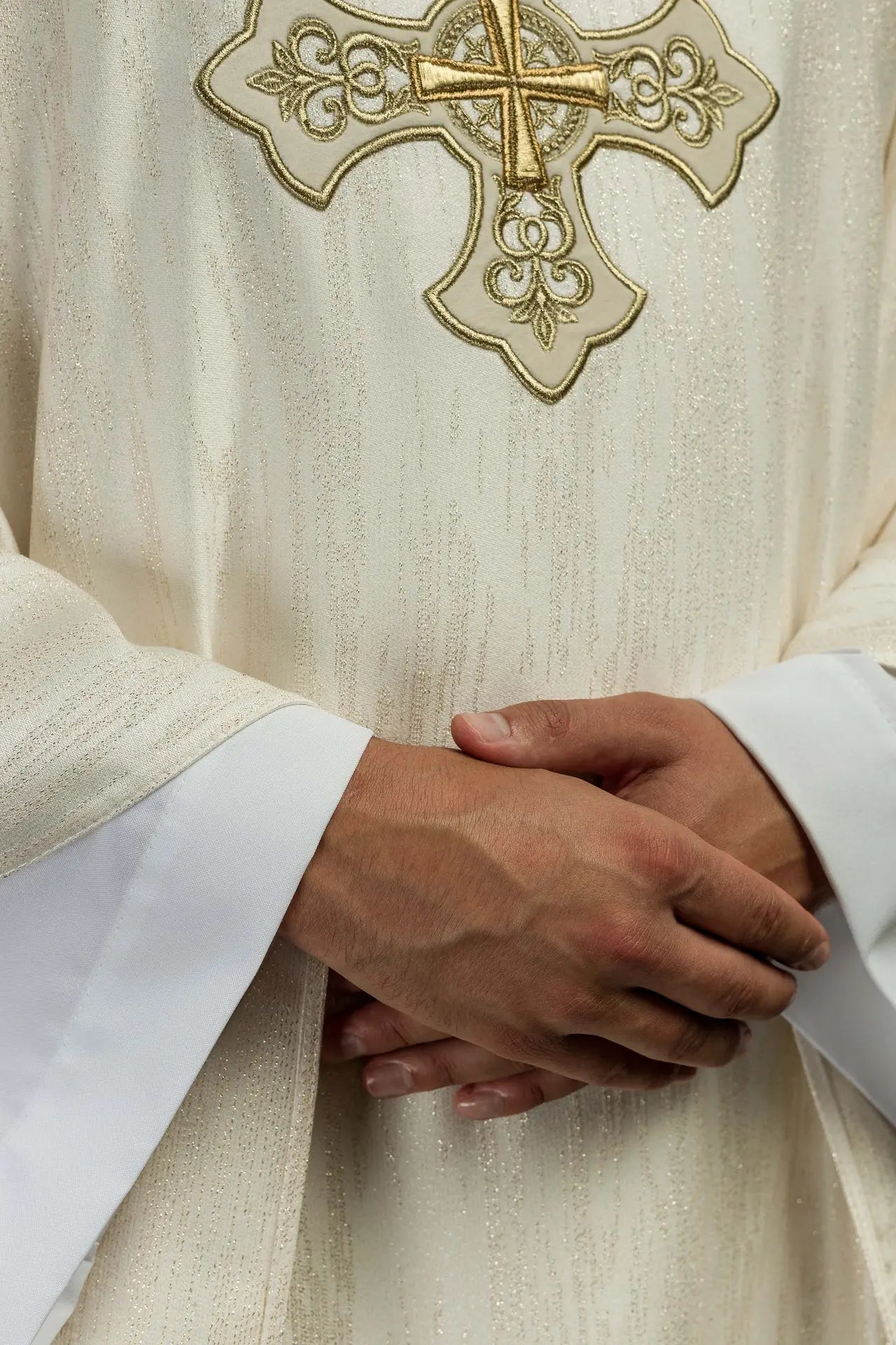 Ecru liturgical chasuble with an embroidered cross motif on decorative fabric