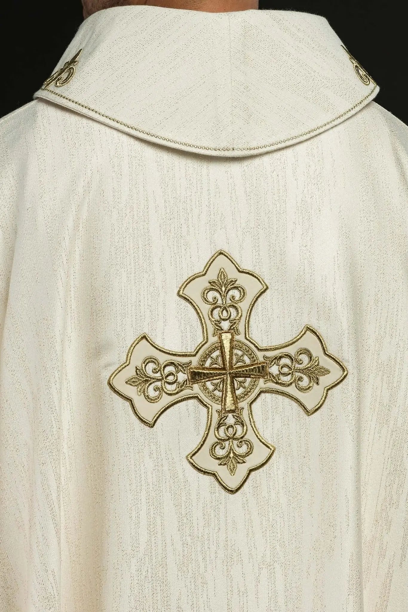 Ecru liturgical chasuble with an embroidered cross motif on decorative fabric