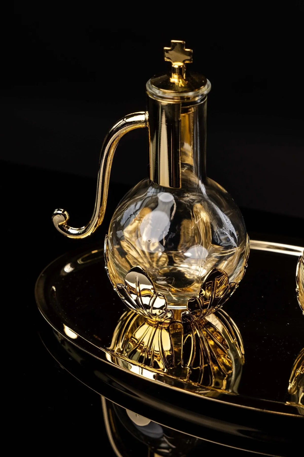 Gold liturgical cruet with floral accents and cross lid, close-up view