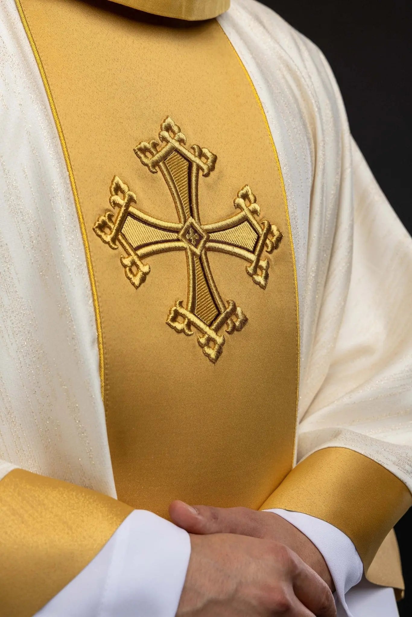 Ecru chasuble with embroidered cross motif and gold band on decorative fabric