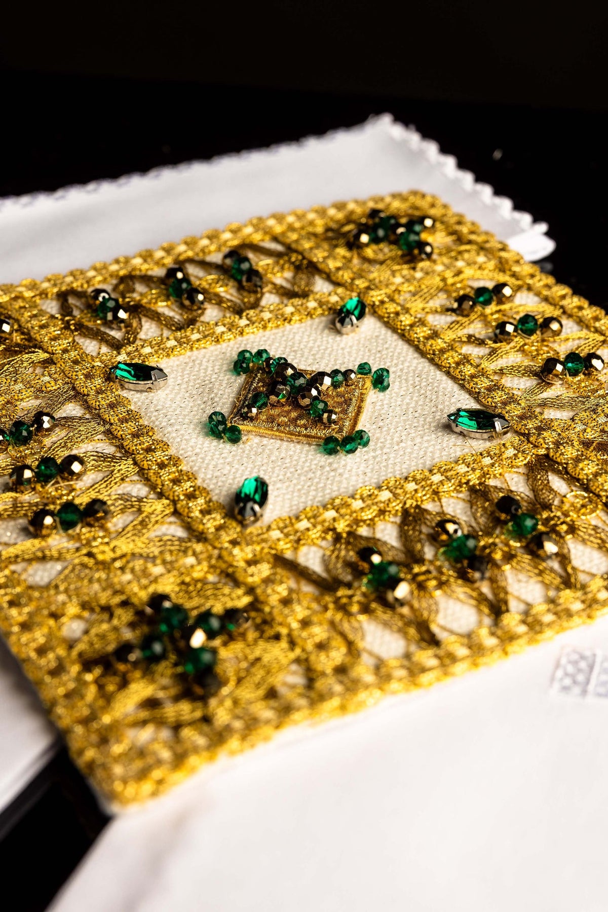 Branco conjunto de alfaias litúrgicas com pedras naturais, bordado dourado e pedras verdes, close-up