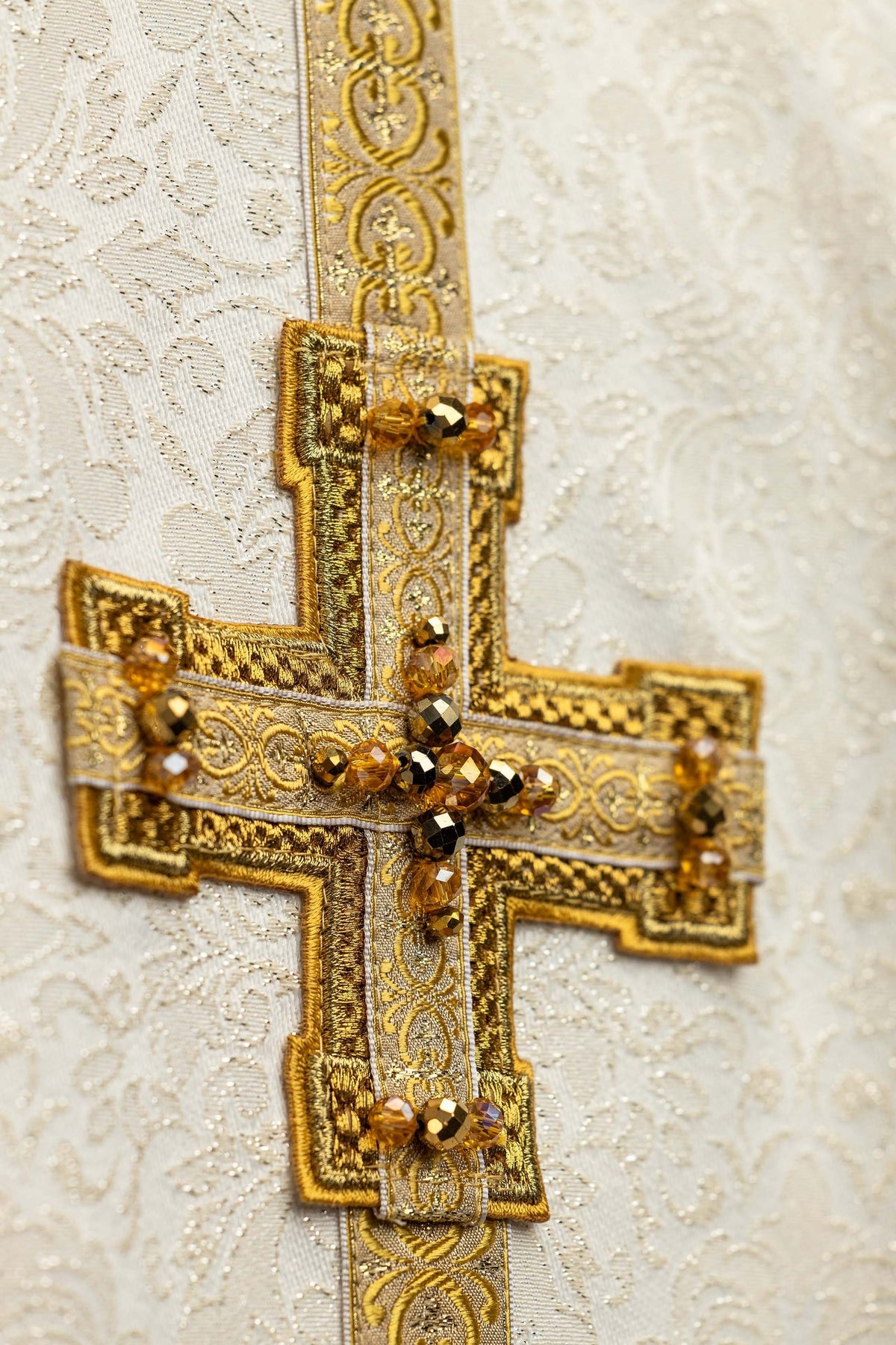 Ecru chasuble with dimensional cross and natural stones, close-up view