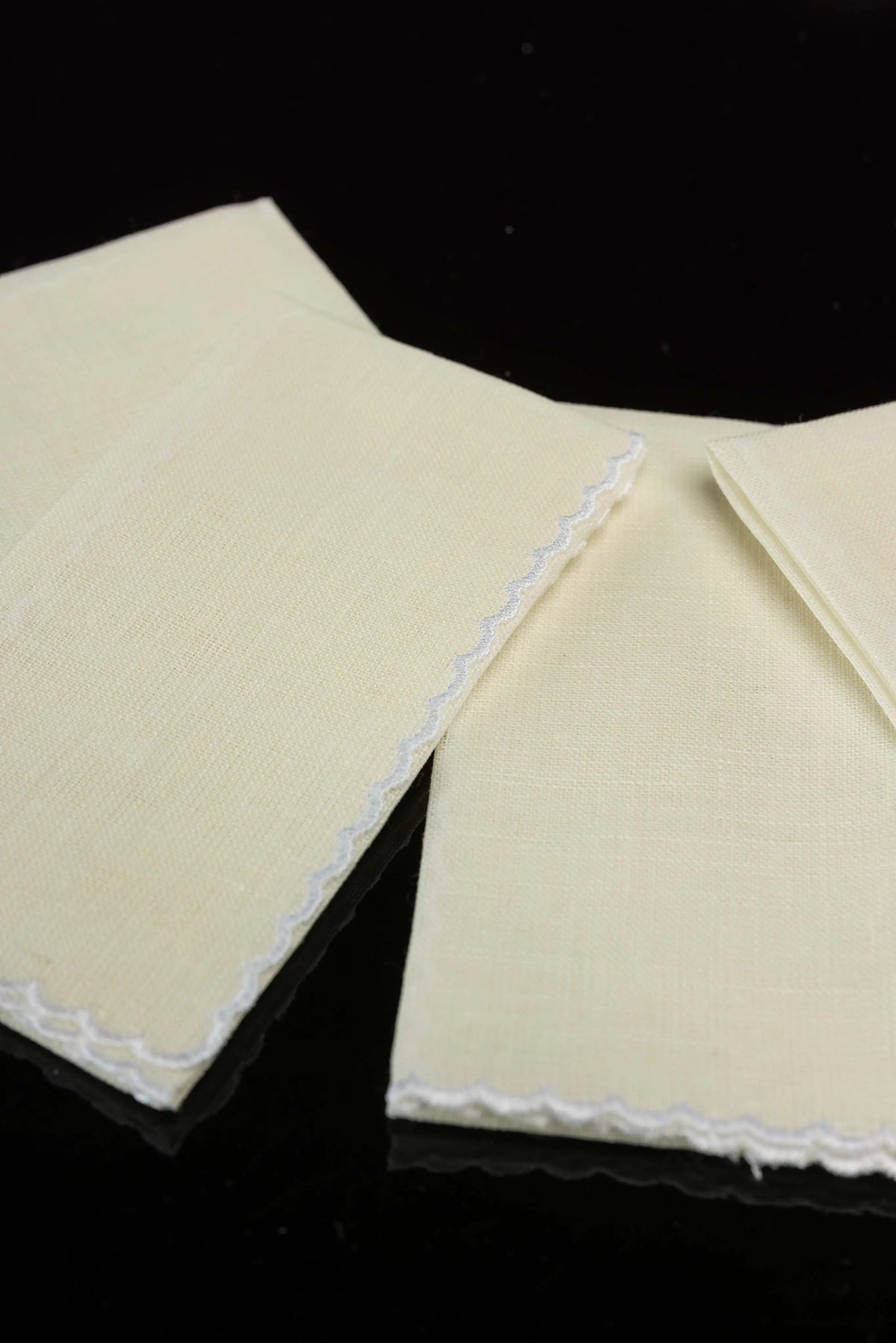 Ecru linen lavabo towels with white scalloped trim, close-up view