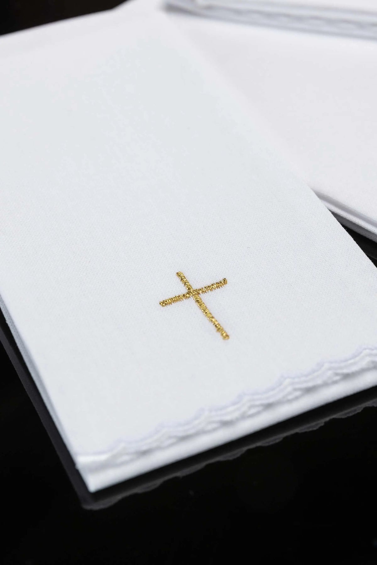White purificator with gold cross embroidery and scalloped edge, close-up