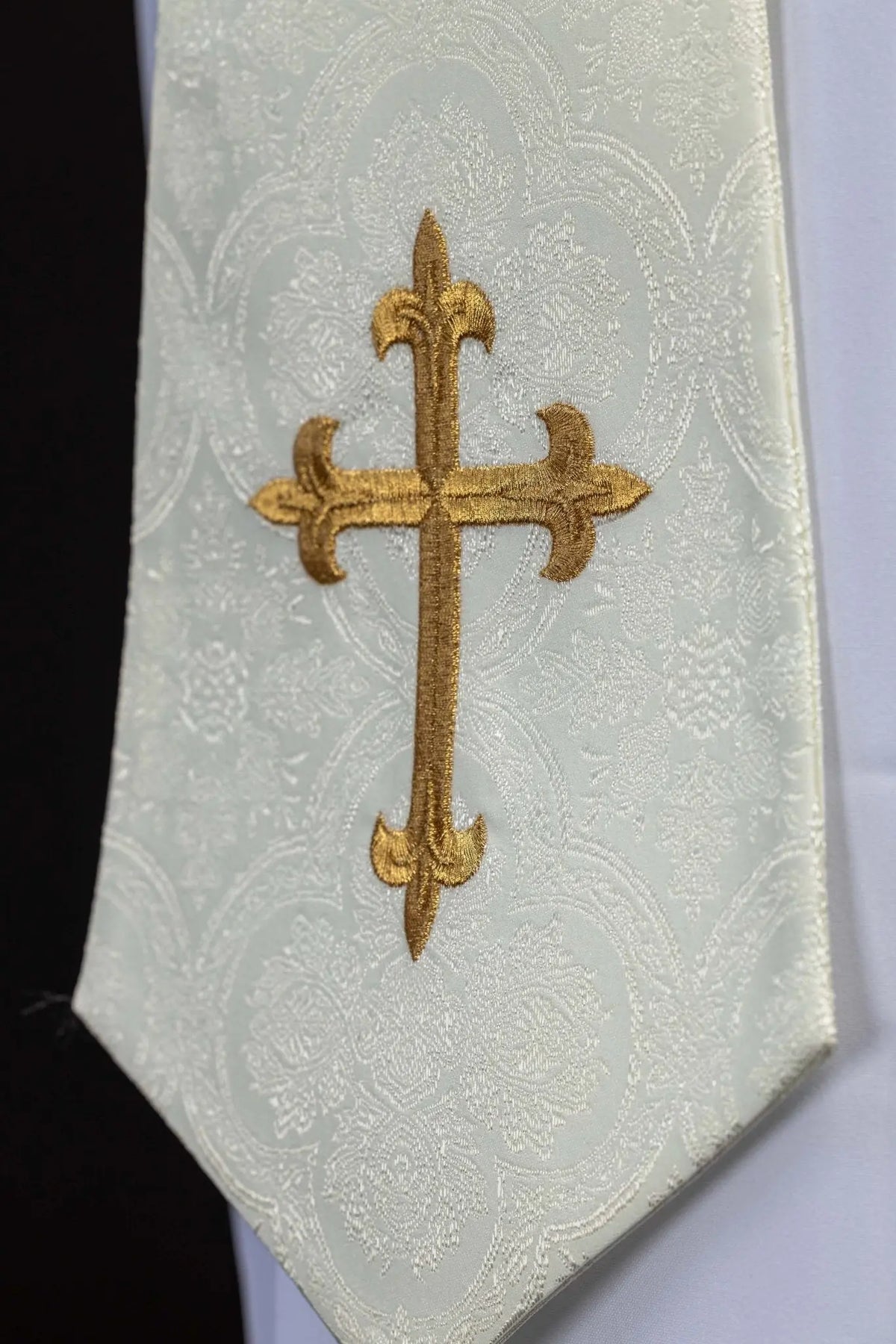 Ecru priest stole with a gold cross, embroidered detail close-up