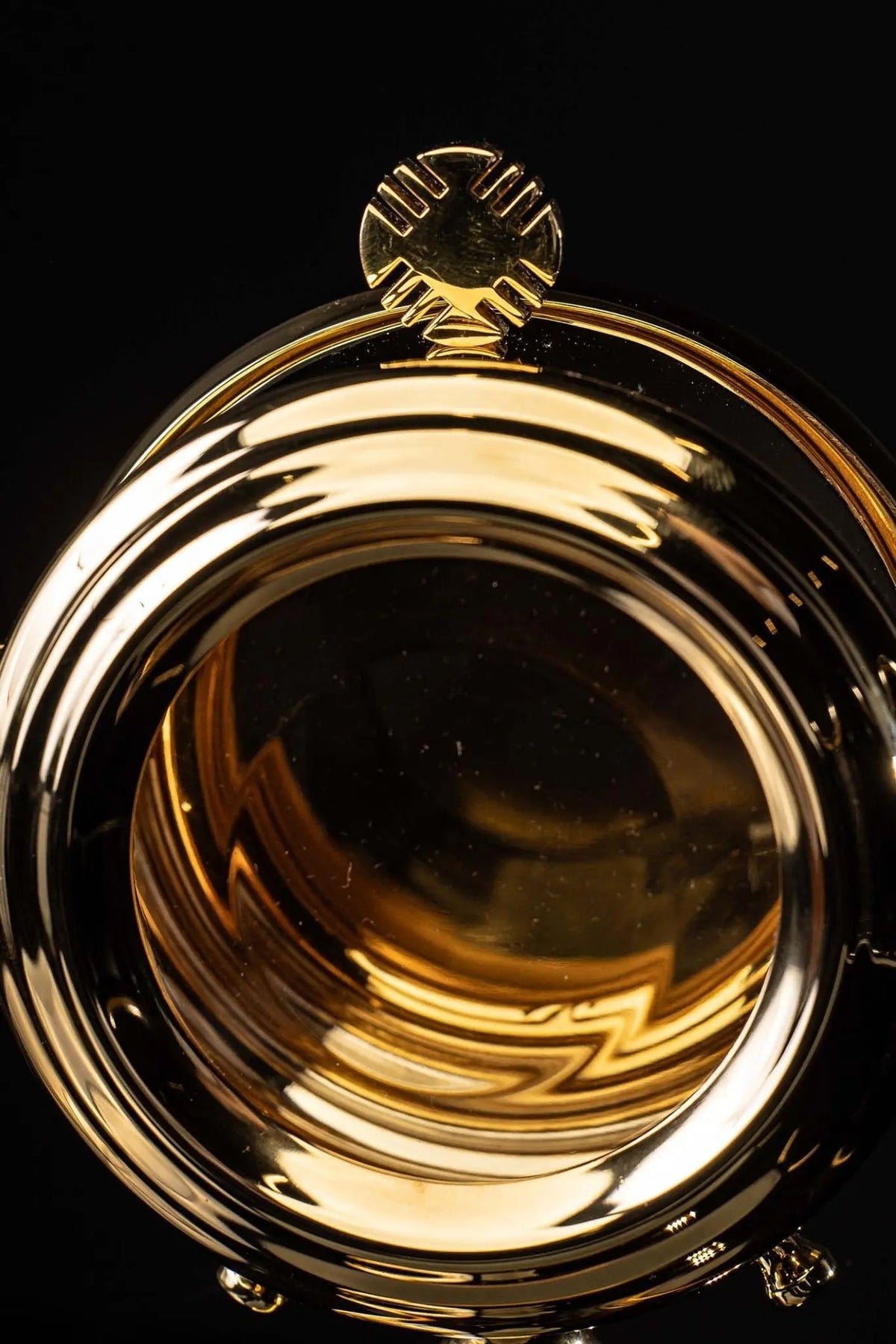 Brass luna holder with cross finial, close-up view