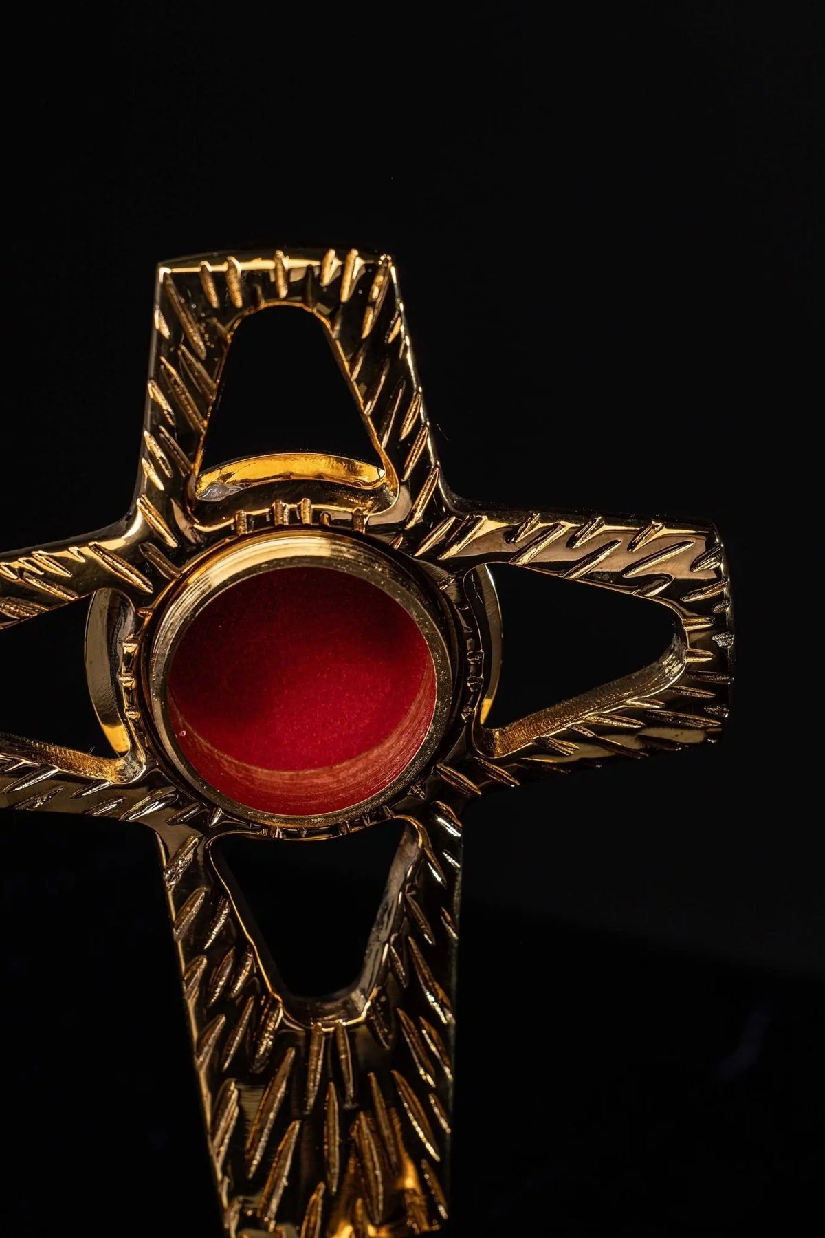 Gilded brass cross-shaped reliquary, close-up front view with radiating engraved details