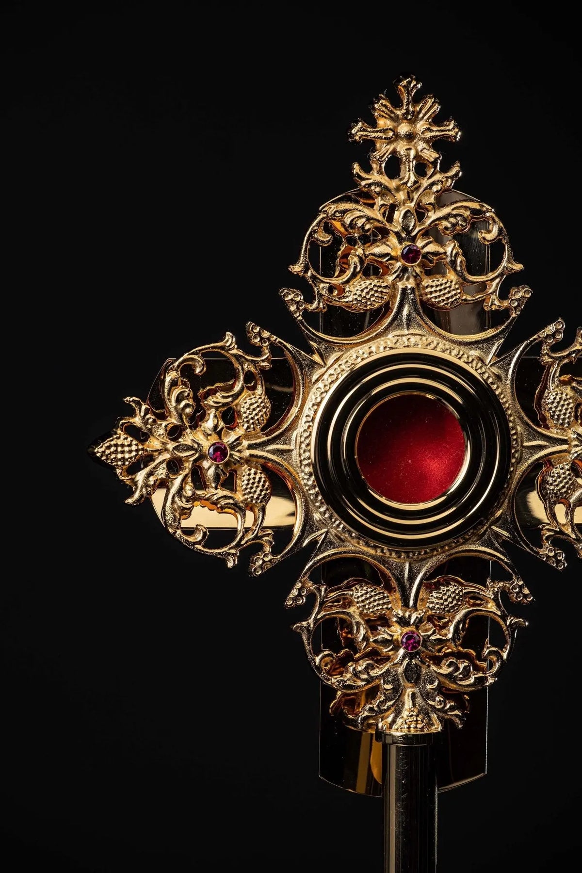 Gilded brass reliquary with red center and floral motifs, front close-up