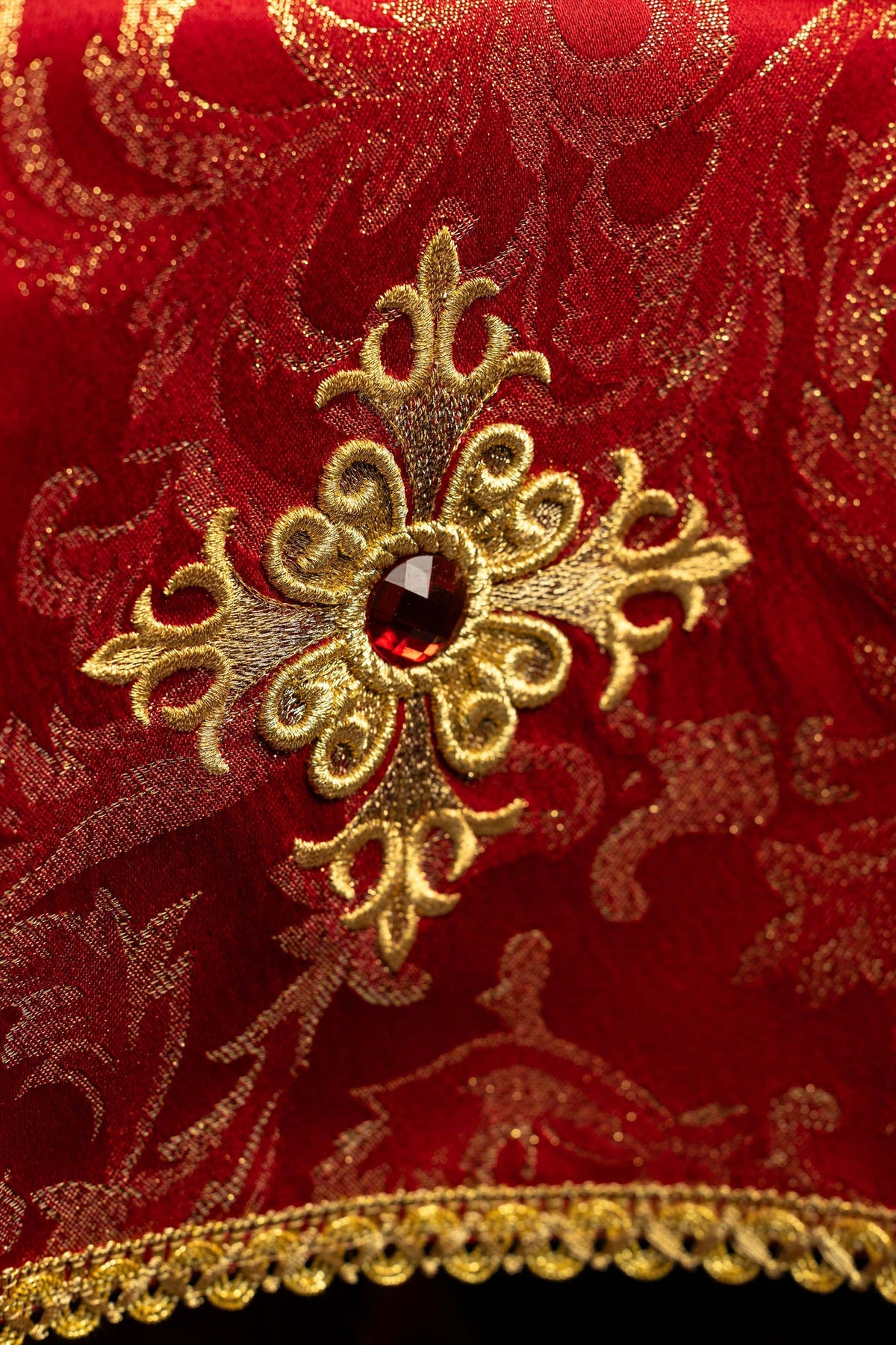 Red chalice veil with gold embroidered cross and red jewel, close-up