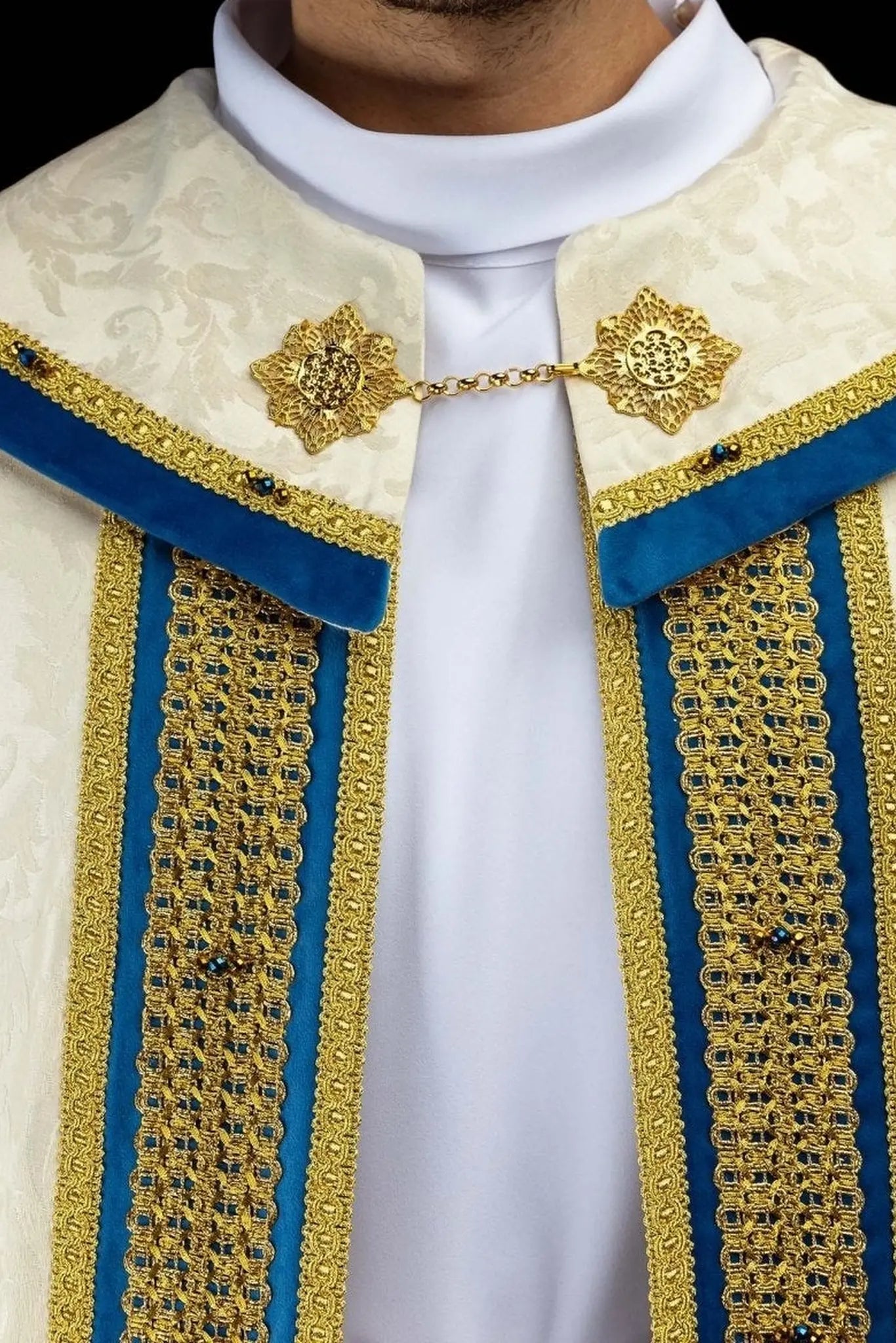 Ecru Marian cope with natural stones and blue velvet trim, part of the Handmade Collection, featuring an ornate metal clasp and gold tassel.