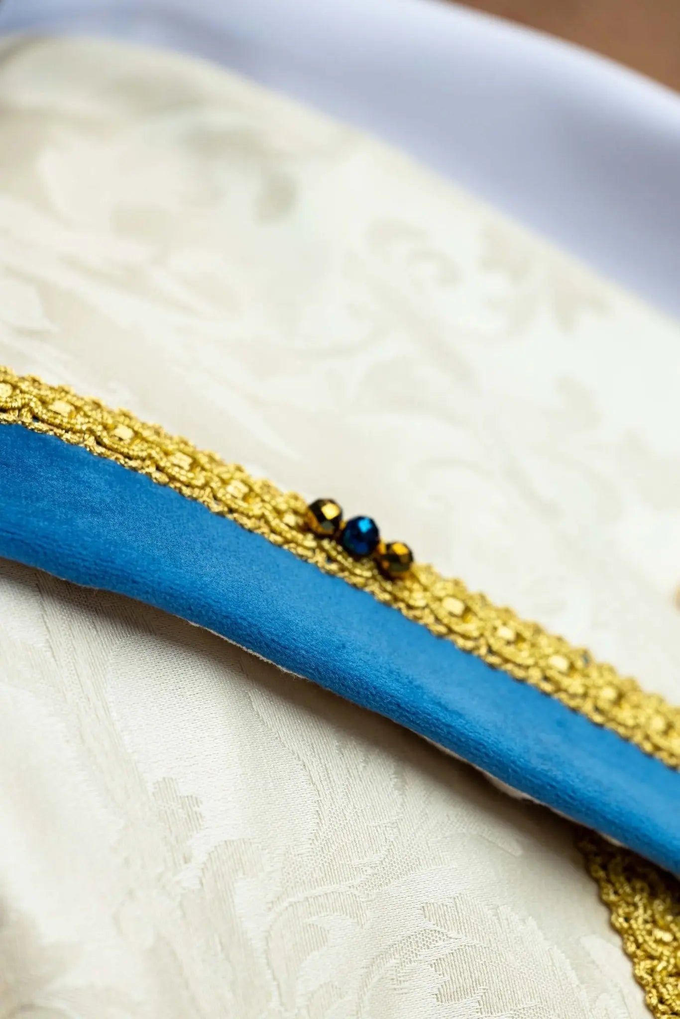 Ecru Marian cope with natural stones and blue velvet trim, part of the Handmade Collection, featuring an ornate metal clasp and gold tassel.