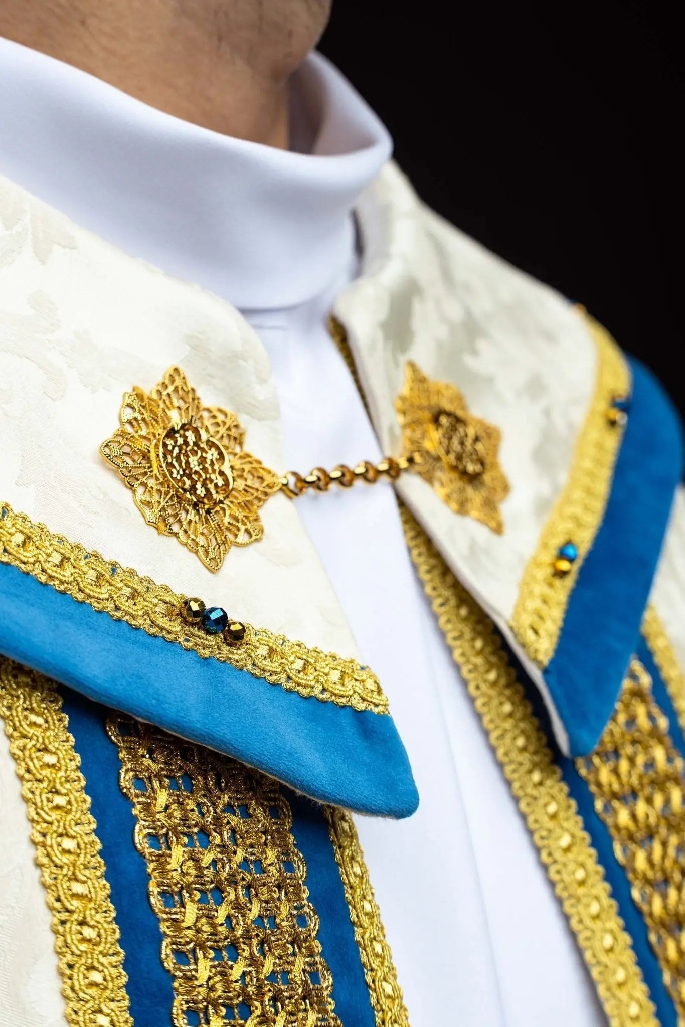 Ecru Marian cope with natural stones and blue velvet trim, part of the Handmade Collection, featuring an ornate metal clasp and gold tassel.